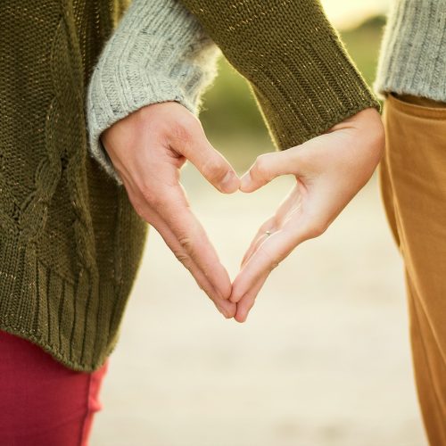 person forming heart shape with their hands